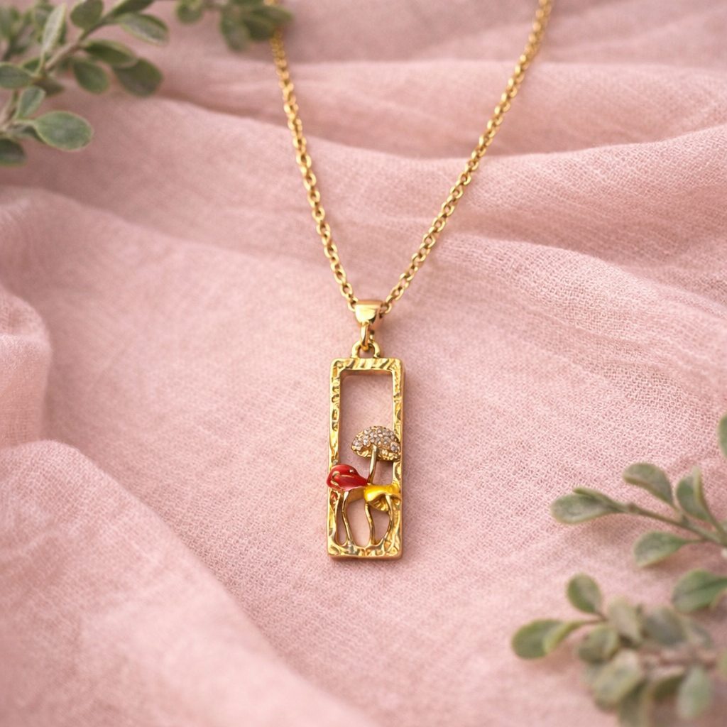 Gold tone necklace with rectangular pendant and colorful enamel mushrooms, whimsical forest-inspired jewelry