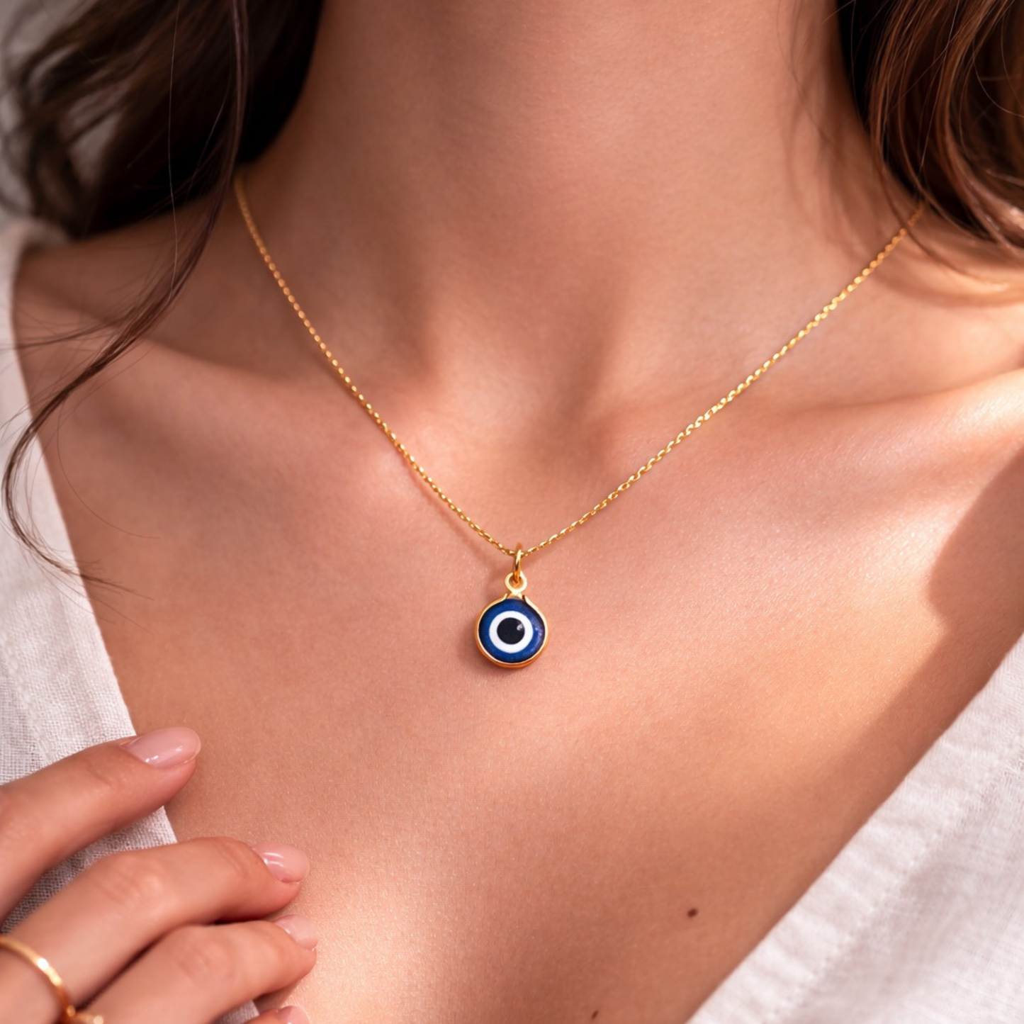 Woman wearing gold tone blue evil eye necklace for everyday protection jewelry styling